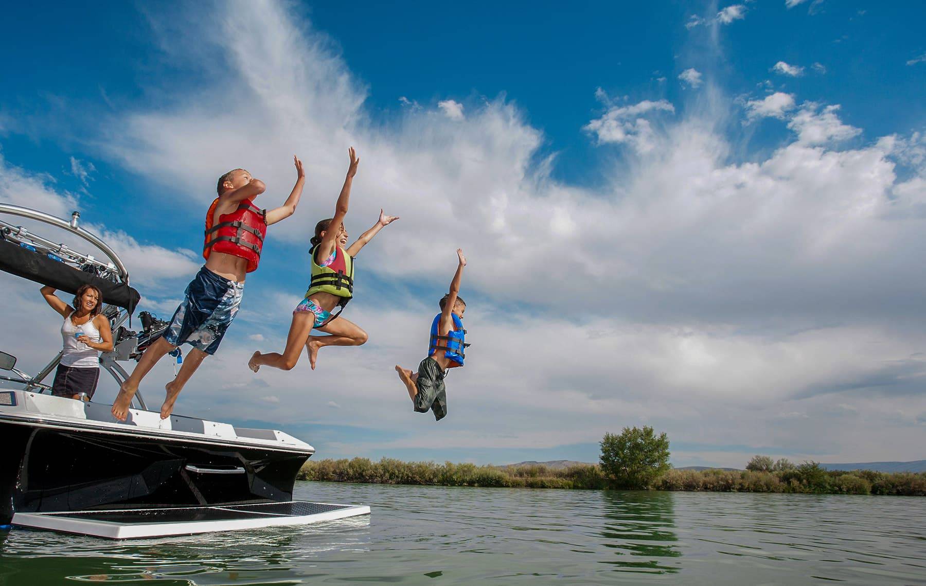 kids jumping into lake from boat